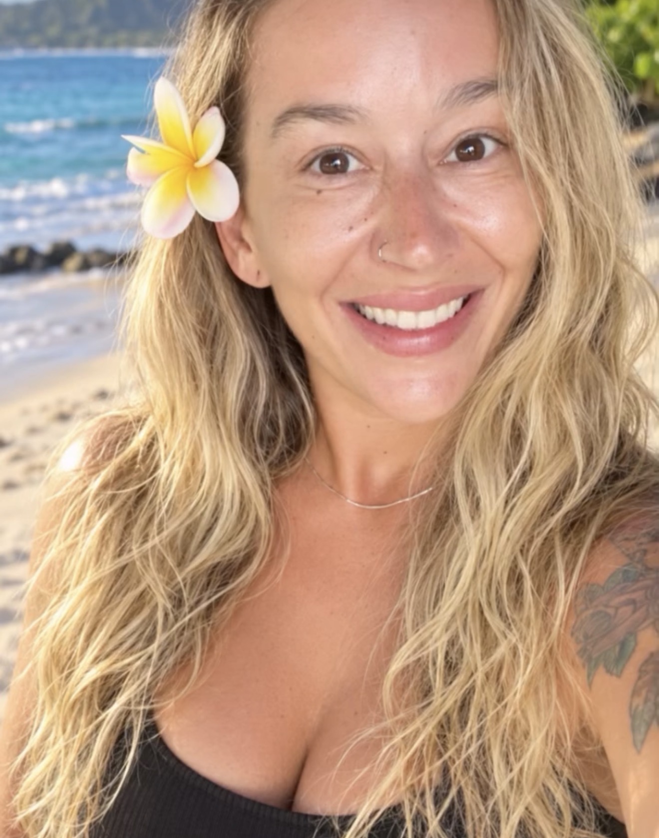 Bree smiling at the beach with a plumeria flower in her hair